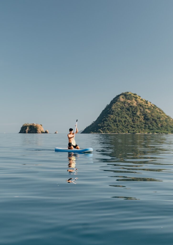 Guest paddleboarding solo near two small islands in calm water
