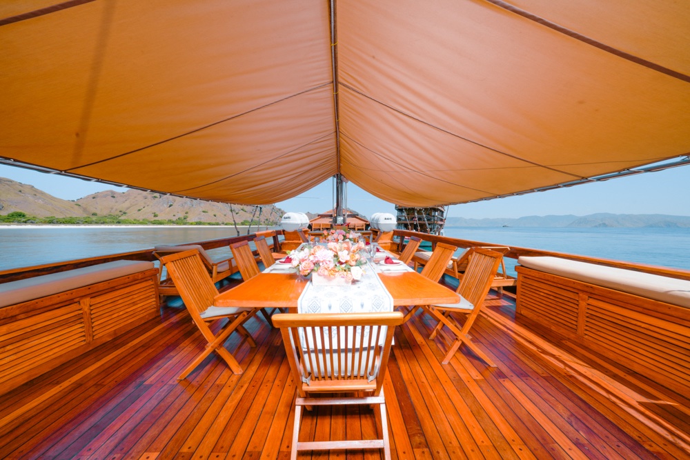 Long dining table set under a canopy on the boat's shaded outdoor deck