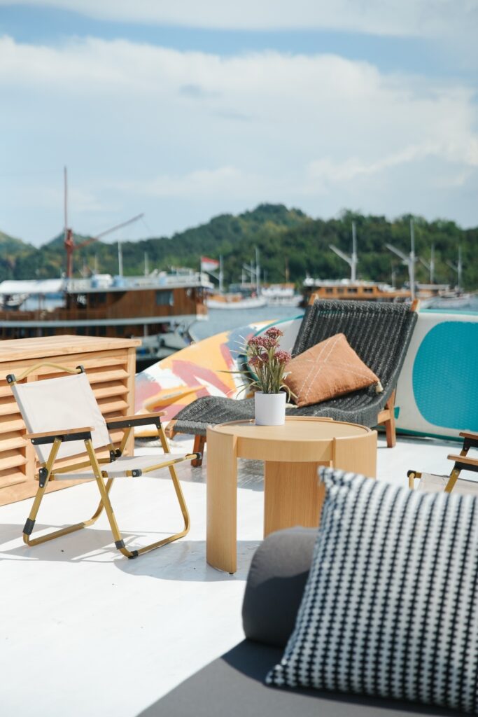 Wooden folding chairs and cushions on a sunny deck overlooking anchored boats