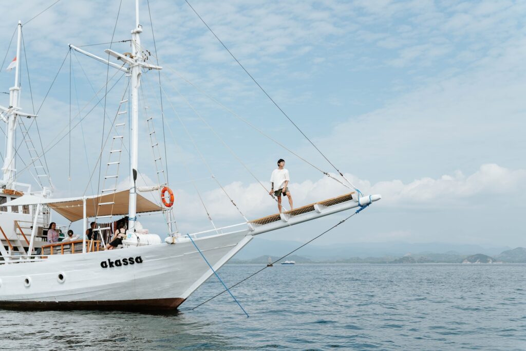 Akassa cruise komodo liveaboard guest standing on the bowsprit netting over open water