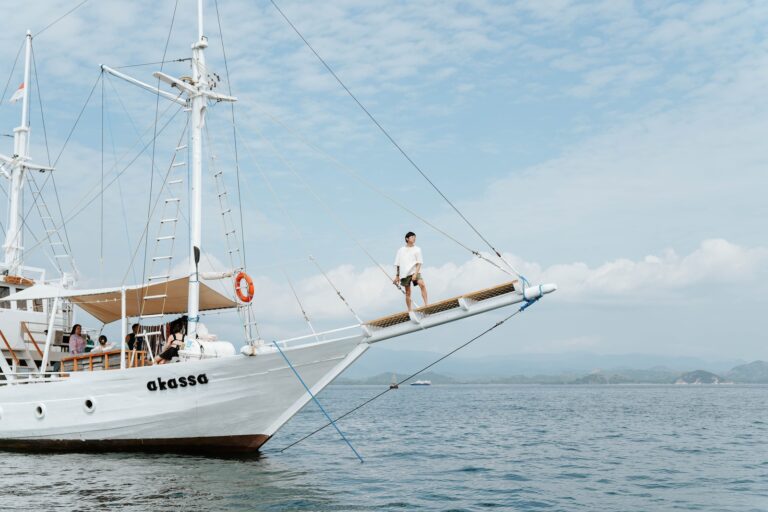 Akassa cruise komodo liveaboard guest standing on the bowsprit netting over open water