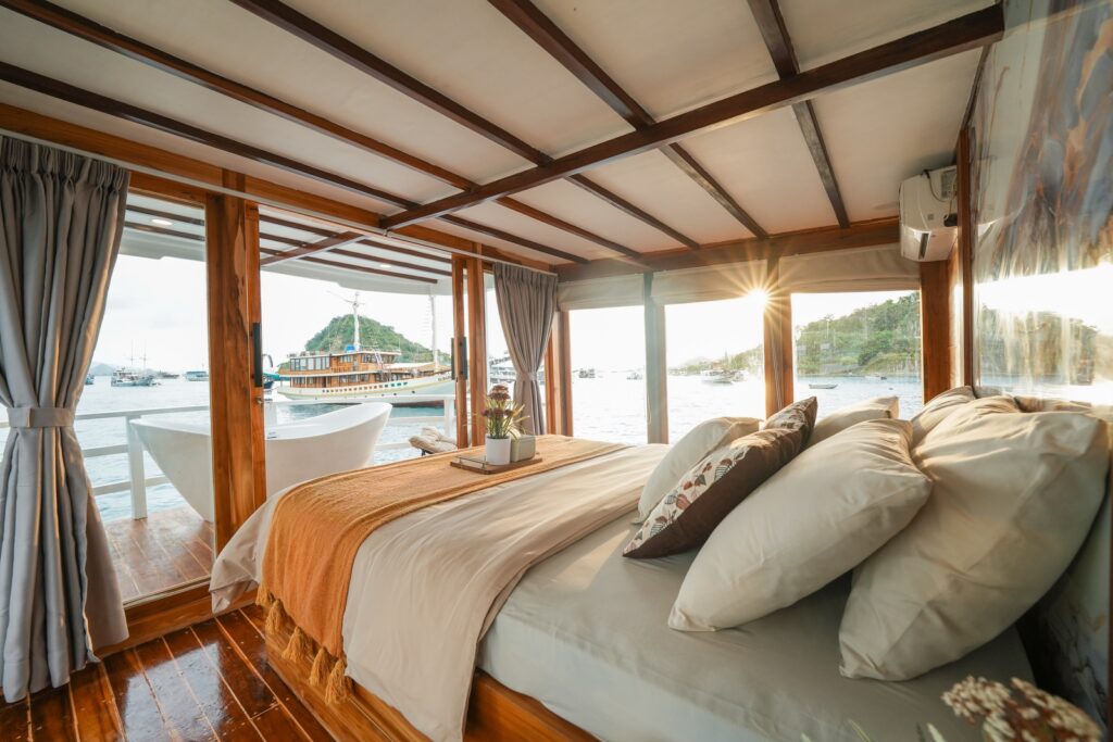 Bedroom with panoramic windows and an outdoor freestanding bathtub in golden light