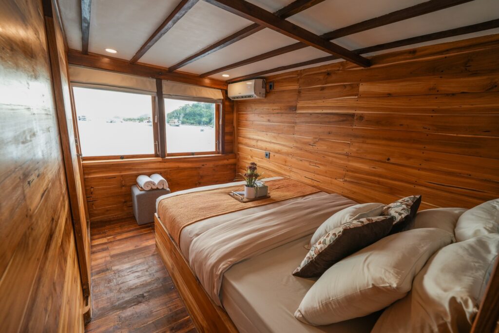 Wood-paneled cabin bedroom with a large window and warm tones