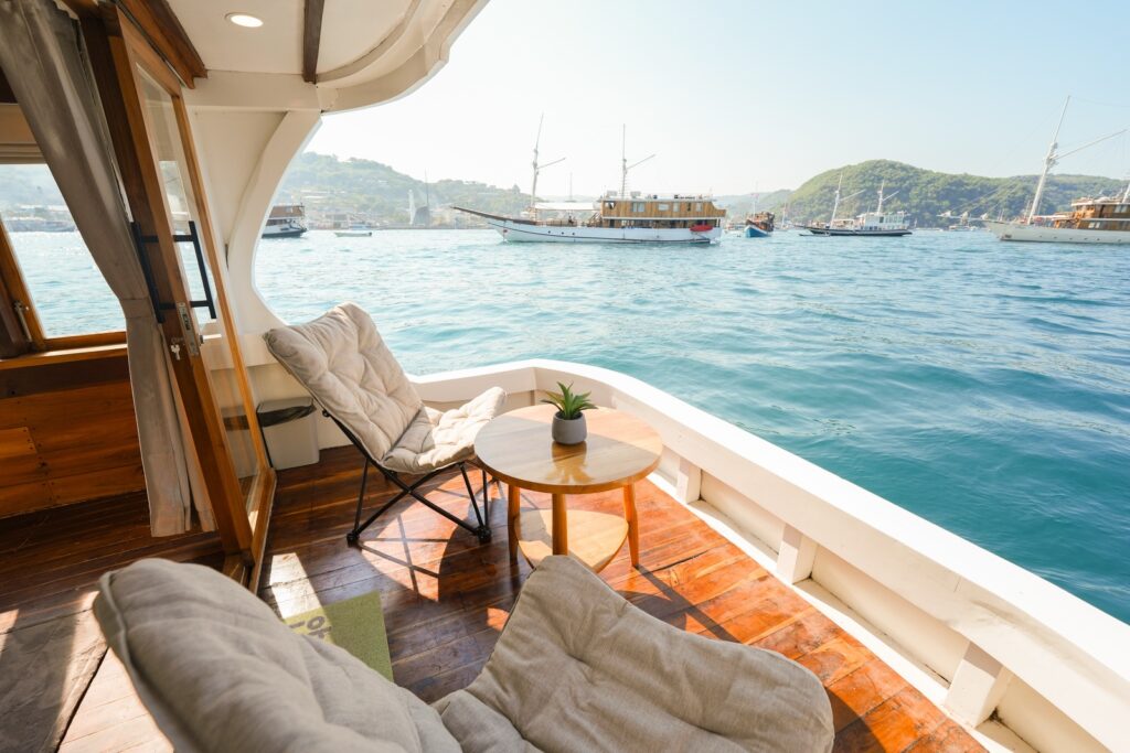 Private balcony with two lounge chairs and a wooden table overlooking the anchorage