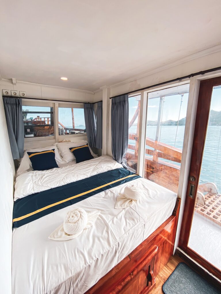 Amalfi cabin bed with a navy and gold runner beside a sliding balcony door