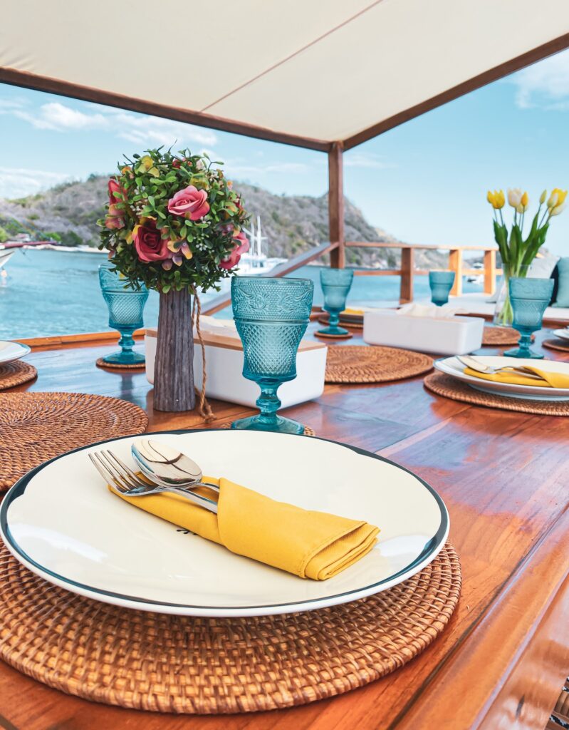 Table setting with a yellow napkin, teal glassware and a floral centerpiece