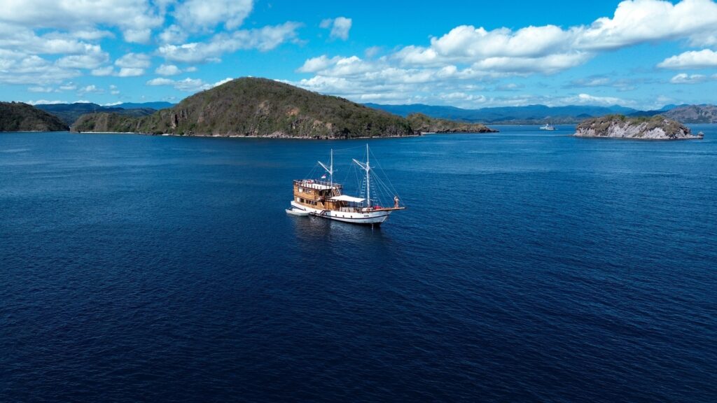 Liveaboard anchored off green islands in Komodo, the Komodo tour planner's real starting point