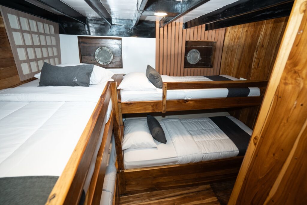 Cabin with a double bed and bunk beds beside porthole wall decor