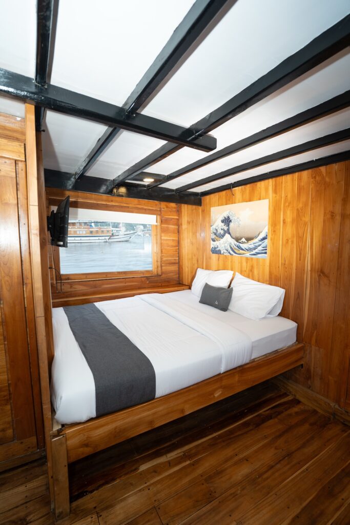 Wood-paneled cabin bed with a grey runner and mounted television