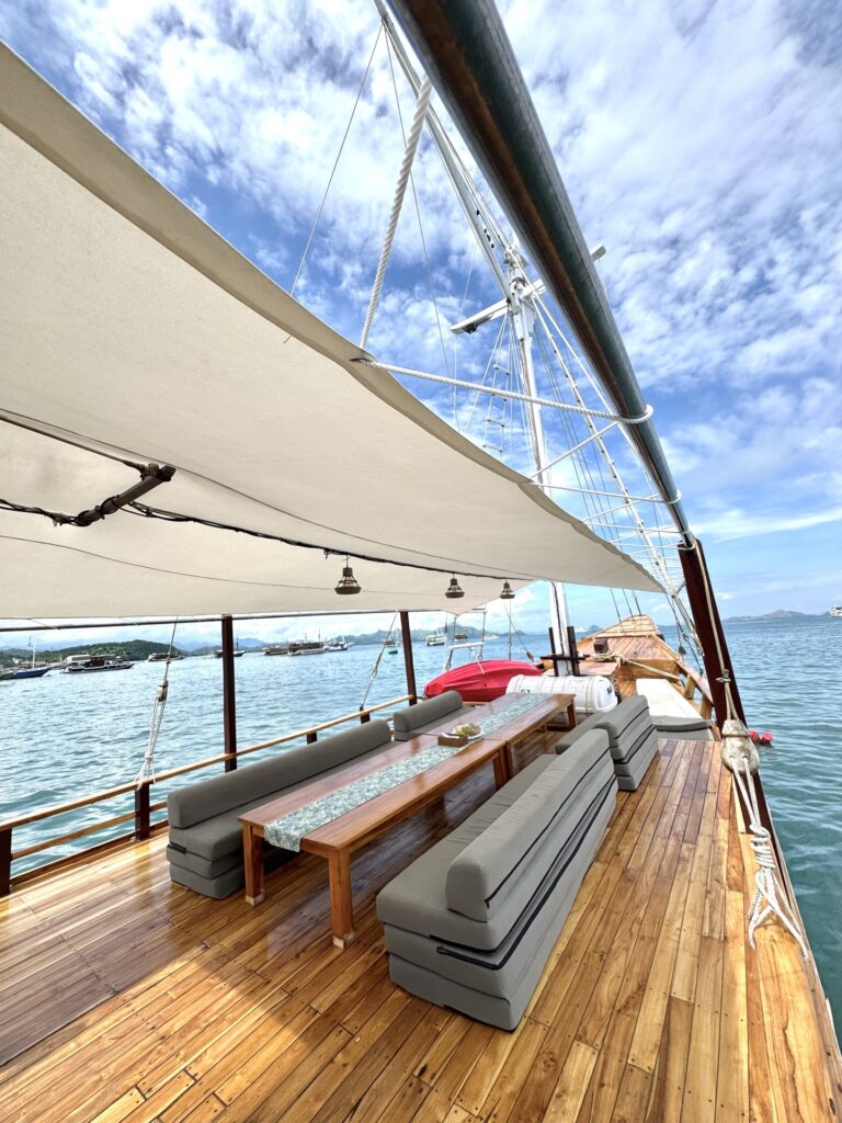 Shaded deck lounge with a long wooden table between grey cushioned benches