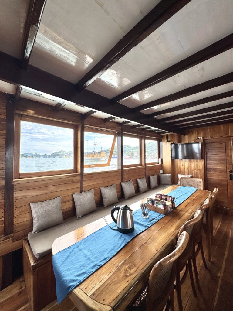 Indoor dining table with a blue runner and bench seating beside ocean-view windows