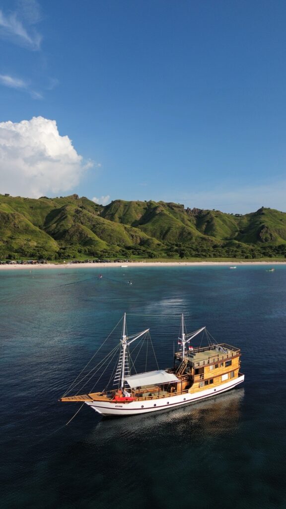 Andalucia anchored near Pink Beach with green hills rising behind