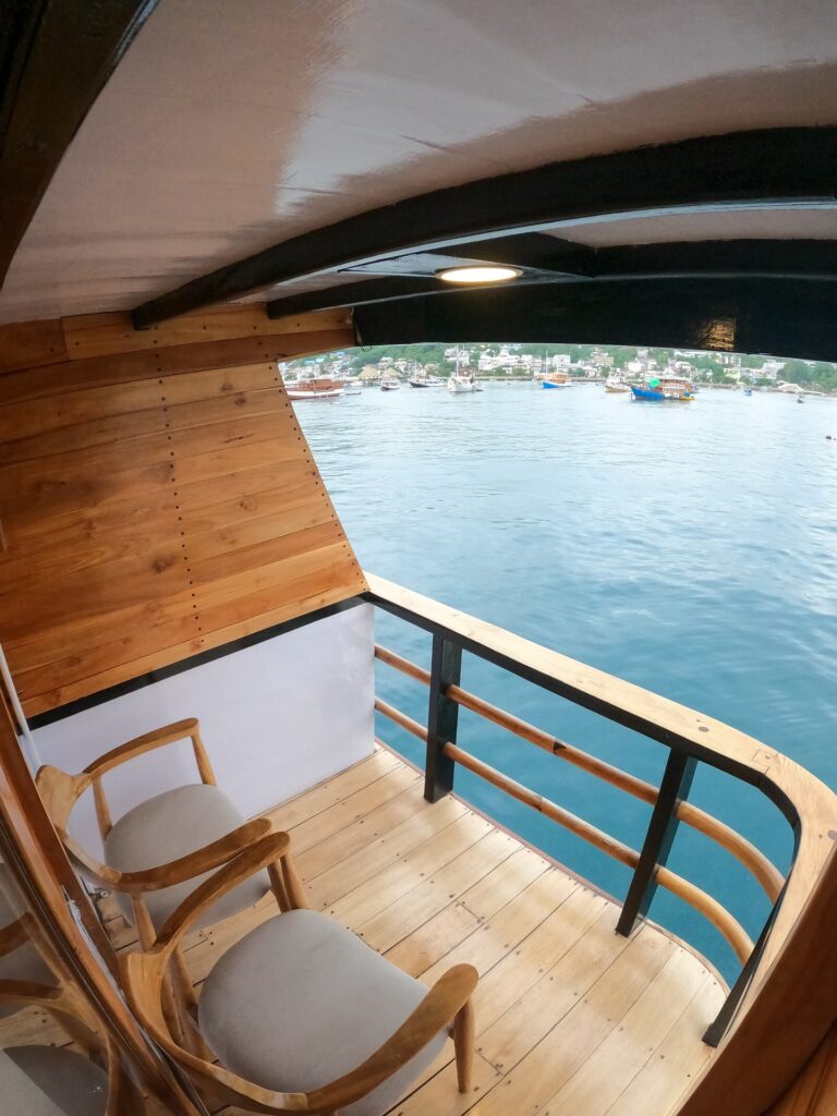 Private balcony aboard Andalucia with two wooden chairs overlooking the harbor