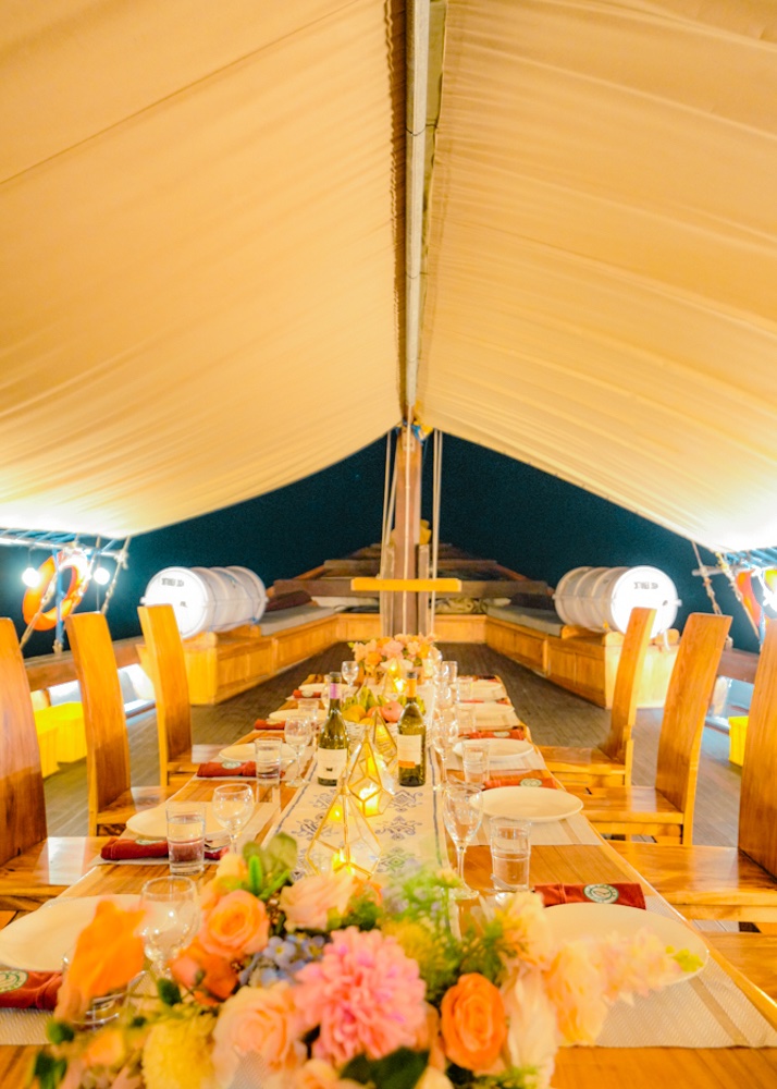 Evening dining table set with candles and floral arrangements under a canopy