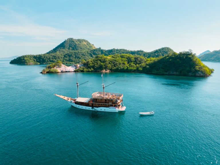 Andamari komodo liveaboard anchored in a bay with a small tender nearby