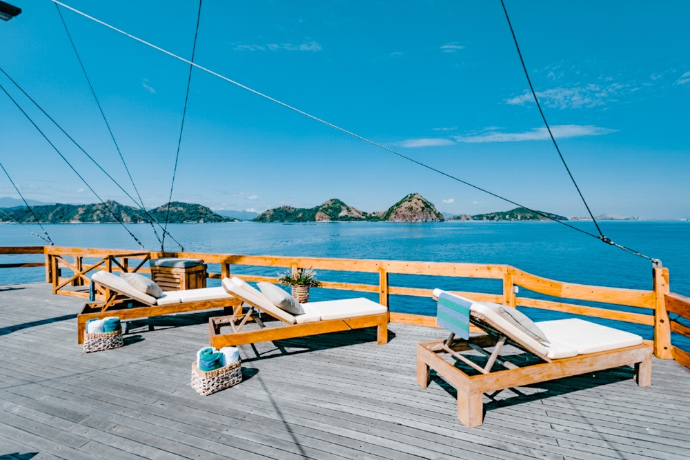 Wooden sun loungers on Andamari's deck with rigging ropes overhead