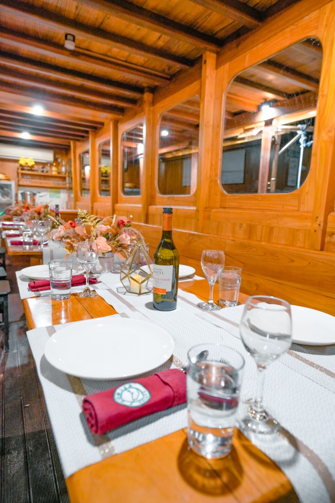 Indoor dining room with a long table set in red napkins and glassware