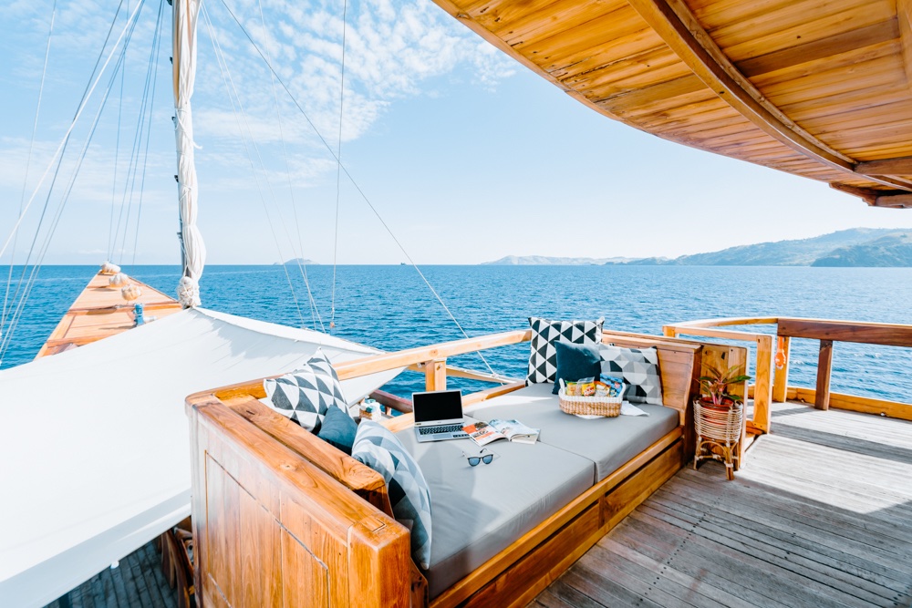 Andamari's deck lounge with a laptop on the cushions and an ocean view