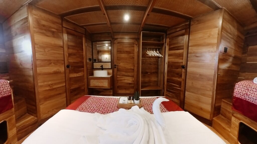 Family cabin bed with red patterned bedding facing a built-in wardrobe
