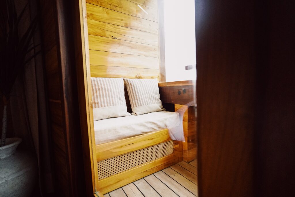 Bed viewed through a wood-framed doorway with cushions against the headboard