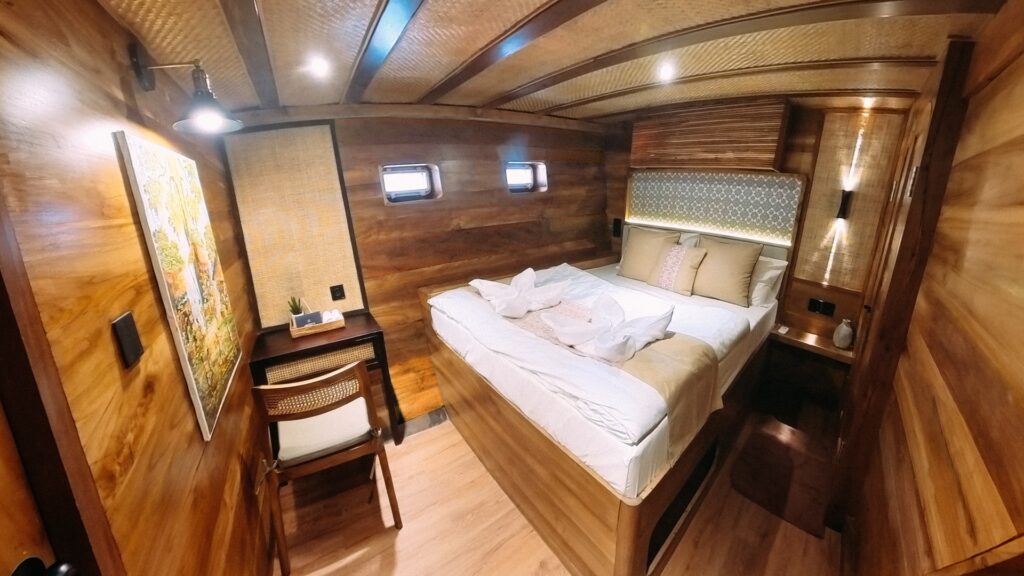 Deluxe cabin bed with small portholes and a framed wall art piece