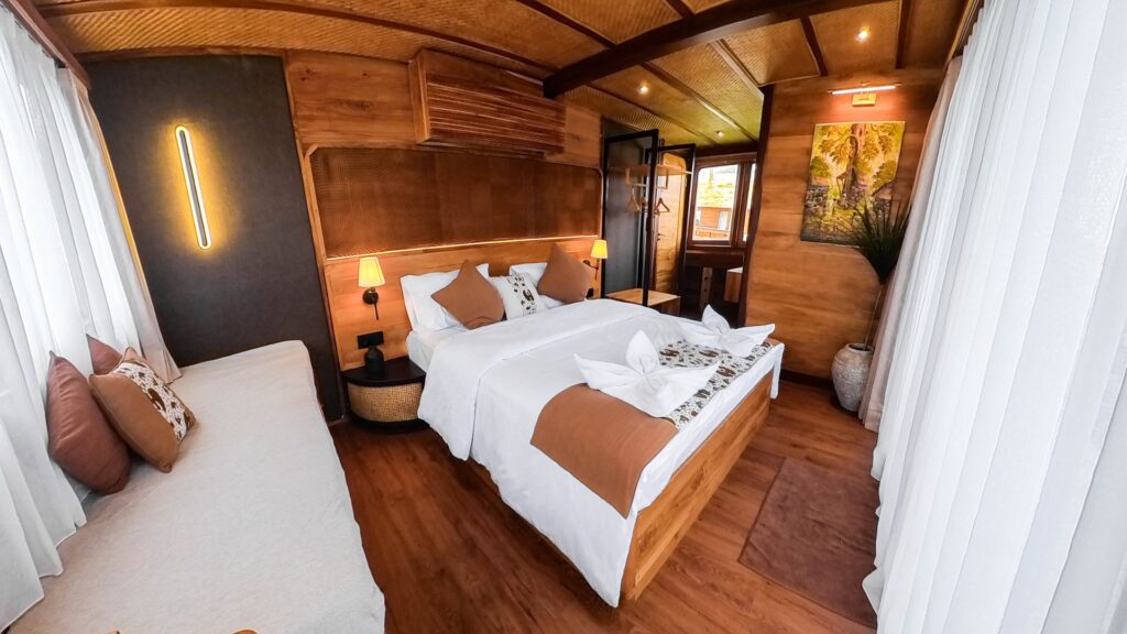 Owners suite bed with a wood headboard and sheer curtains on either side