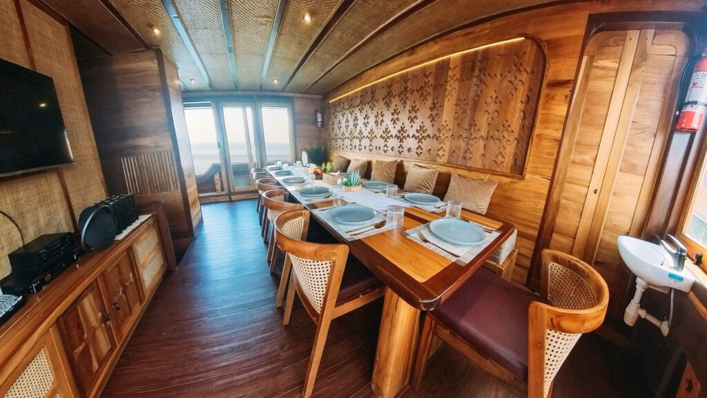 Indoor dining room with a long table, carved wall panel and rattan chairs