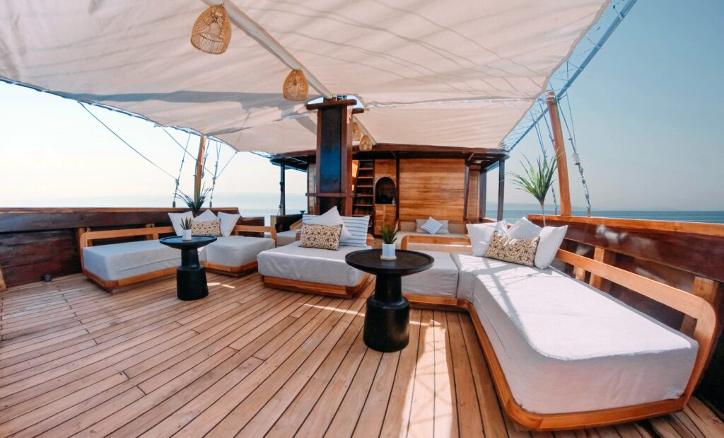 Shaded outdoor lounge deck with white cushioned sofas and round side tables