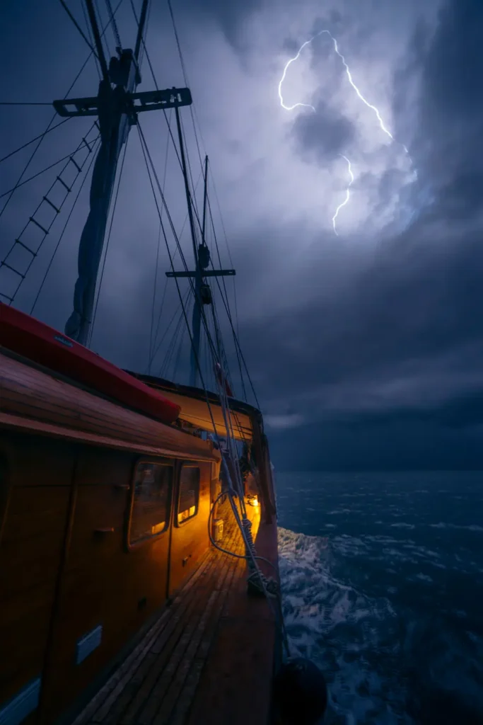 Dramatic lightning storm captured from the Anne Bonny luxury Phinisi while sailing across dark open ocean waters at night in Indonesia.
