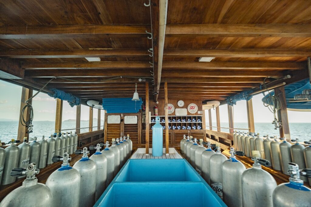 Symmetrical scuba tank setup aboard Cajoma V dive boat with spacious central rinse station and organized equipment layout for diving operations.
