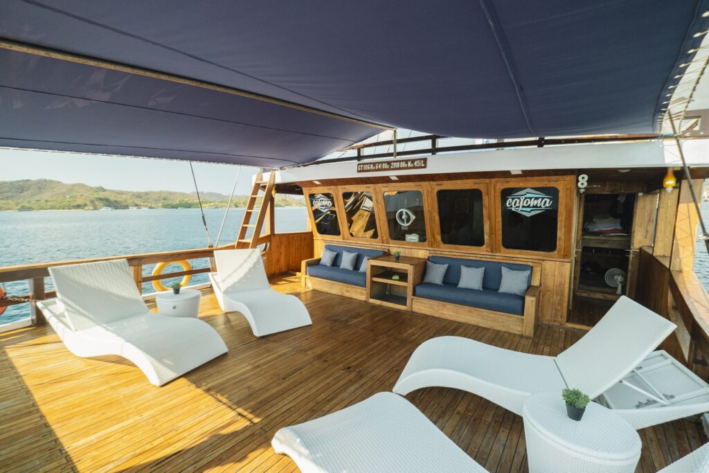 Spacious upper lounge deck on Cajoma V private charter with shaded seating, woven sun loungers, and panoramic ocean surroundings.