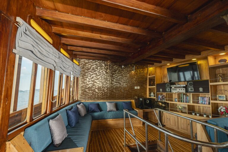 Cozy indoor entertainment lounge aboard Cajoma V private yacht featuring wraparound seating, bookshelf decor, and a dedicated multimedia area.