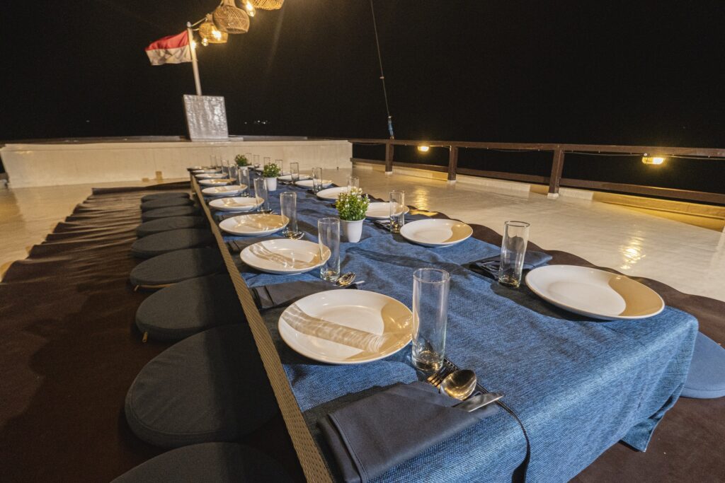 Private rooftop dining setup aboard Cajoma V featuring floor seating, elegant table arrangements, and warm lantern lighting for an intimate evening experience at sea.