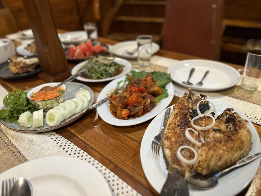 Dining table spread with grilled fish, vegetables and side dishes