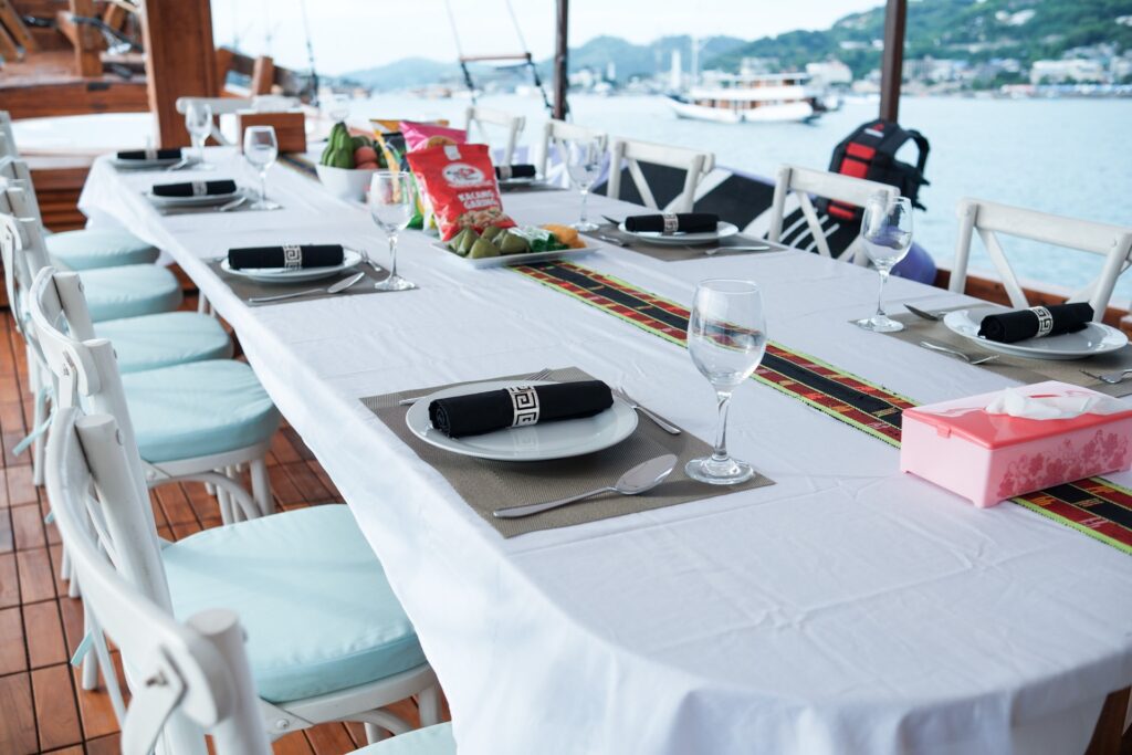 Outdoor dining table set with black napkins and blue cushioned chairs