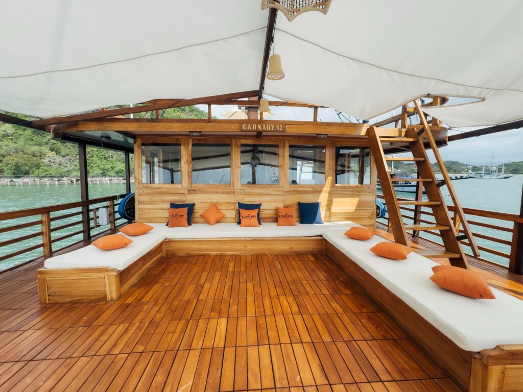 Shaded stern deck seating with orange cushions and a wooden ladder