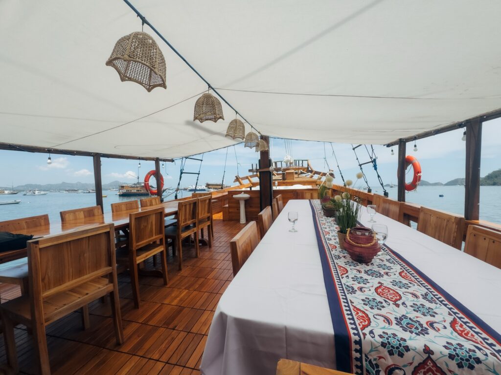 Outdoor dining table set under woven pendant lights with a patterned runner