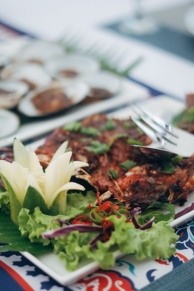 Grilled seafood dish garnished with chili and lettuce on a patterned plate
