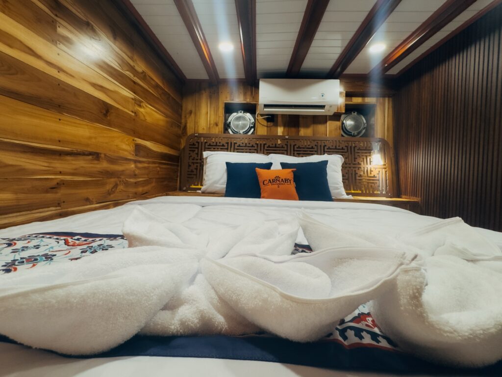 Superior cabin bed with white linens and an orange and navy pillow