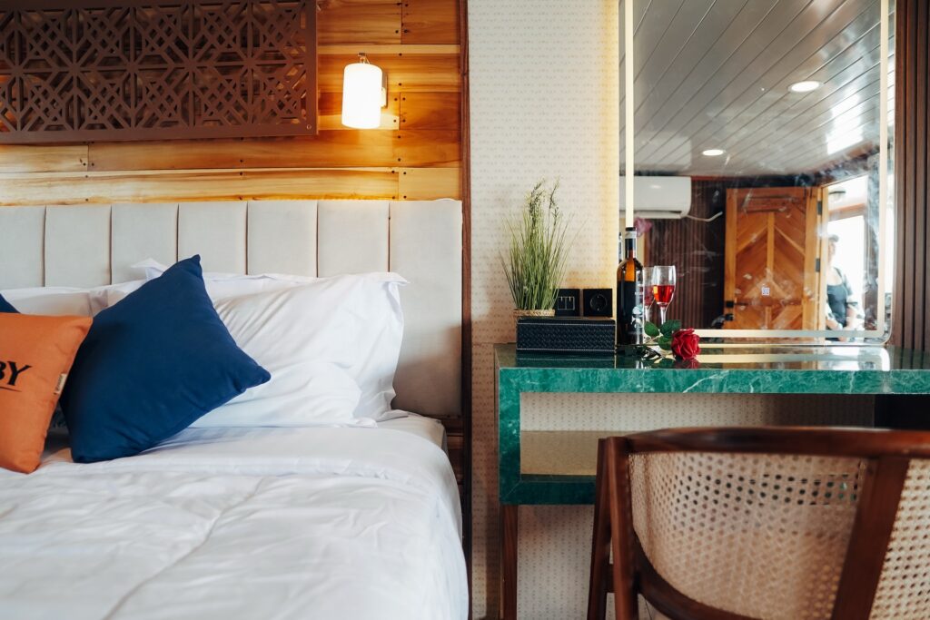 Bed with orange and navy pillows beside a green marbled vanity desk