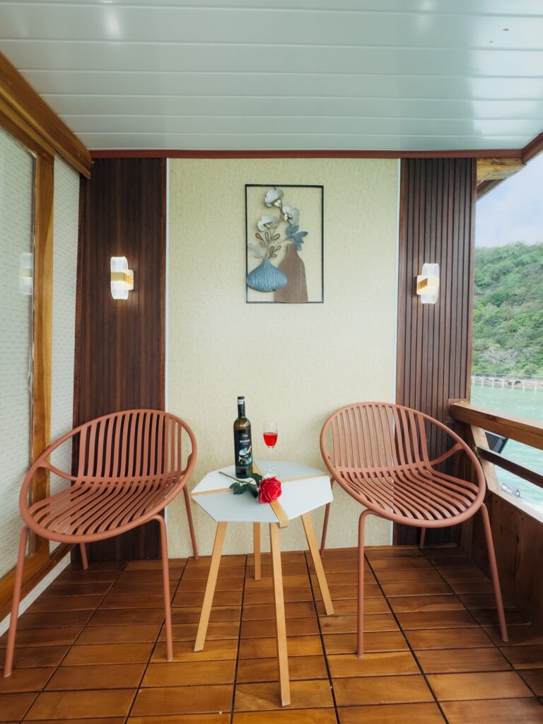 Private balcony with two chairs, a small table and a glass of wine