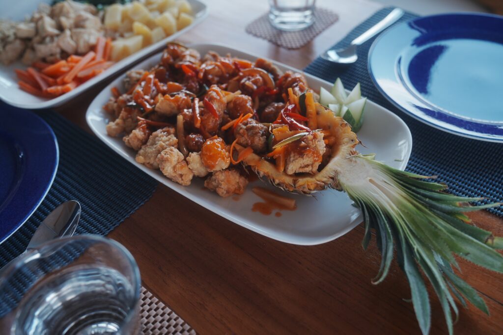 Sweet and sour seafood dish served in a carved pineapple on a dining table