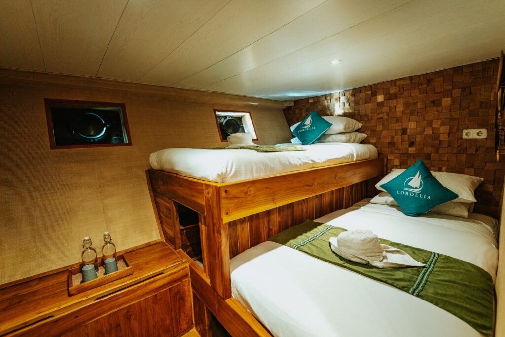 Air conditioned bunk cabin with a wooden bunk bed and porthole windows