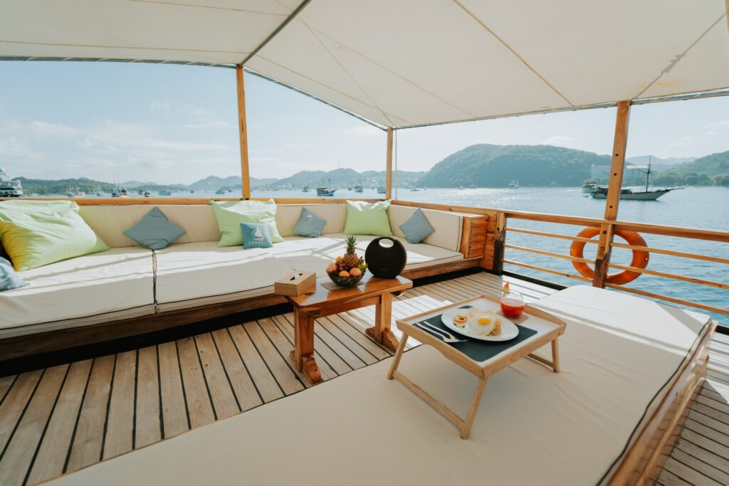 Shaded deck lounge on the Cordelia phinisi with cushioned seating and a breakfast tray