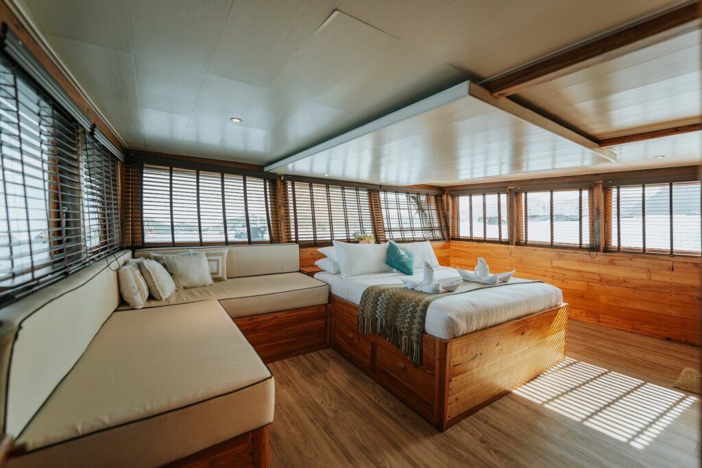 Cordelia phinisi master bedroom with a wooden bed and built in daybed seating