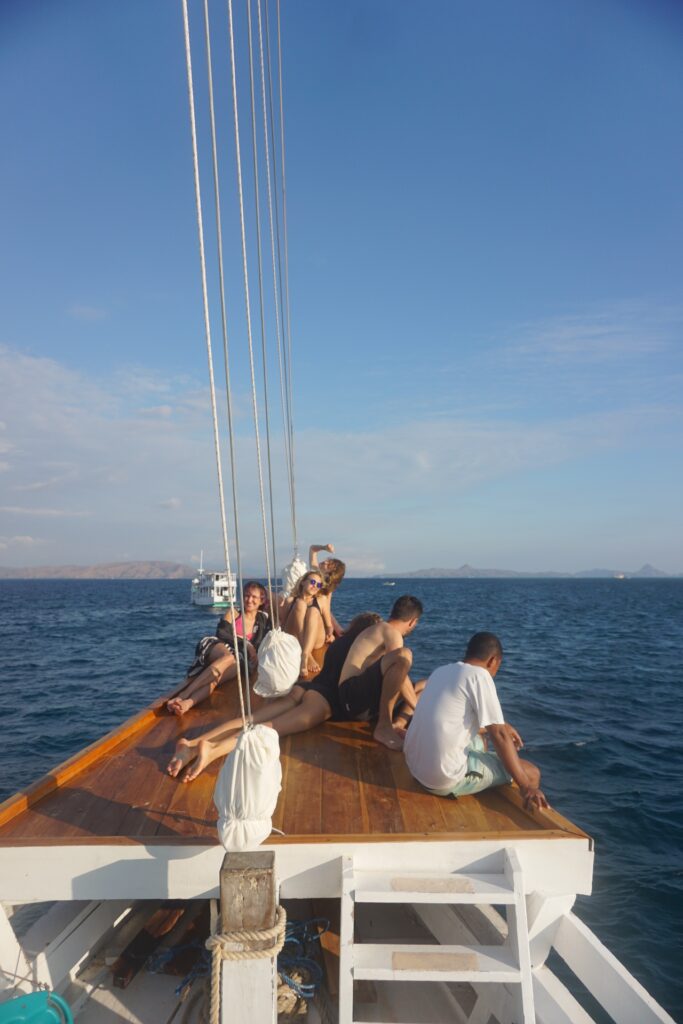 Guests relaxing on the wooden bowsprit of the Dinara with ocean views