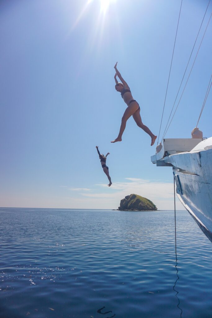 Two guests jumping off the bow of the Dinara into the ocean