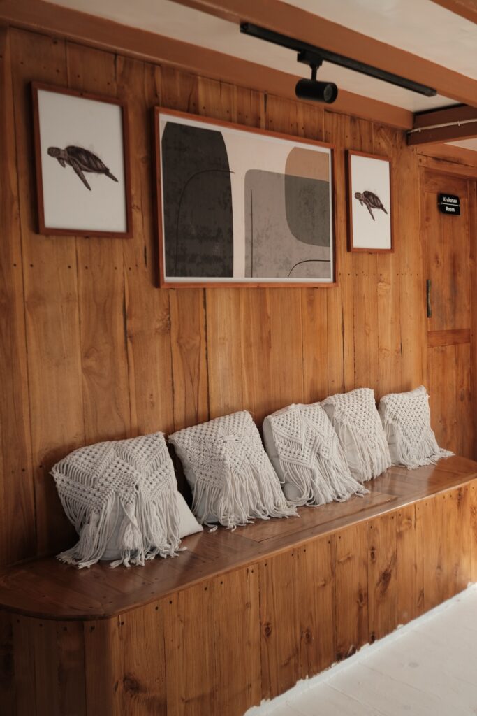 Wooden hallway with white macrame pillows on a bench and framed wall art