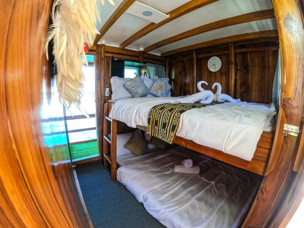 Triple family room with a double bed below and a single bunk with swan towel art