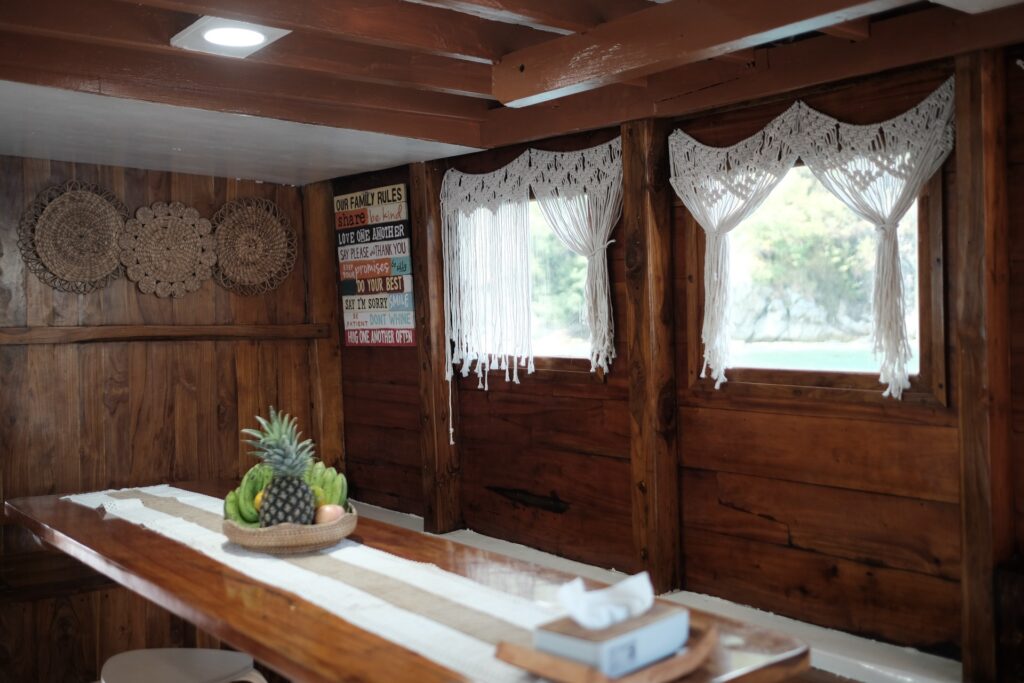 Wooden dining room with macrame curtains and a fresh fruit bowl on the table